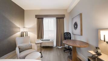 Une chambre d’hôtel équipée d’un lit, d’un bureau, d’une chaise, d’une lampe, d’un téléphone et d’une fenêtre avec des rideaux.