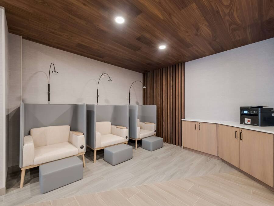 A modern spa area with three cushioned seating areas, wooden cabinets, and a ceiling with recessed lighting.