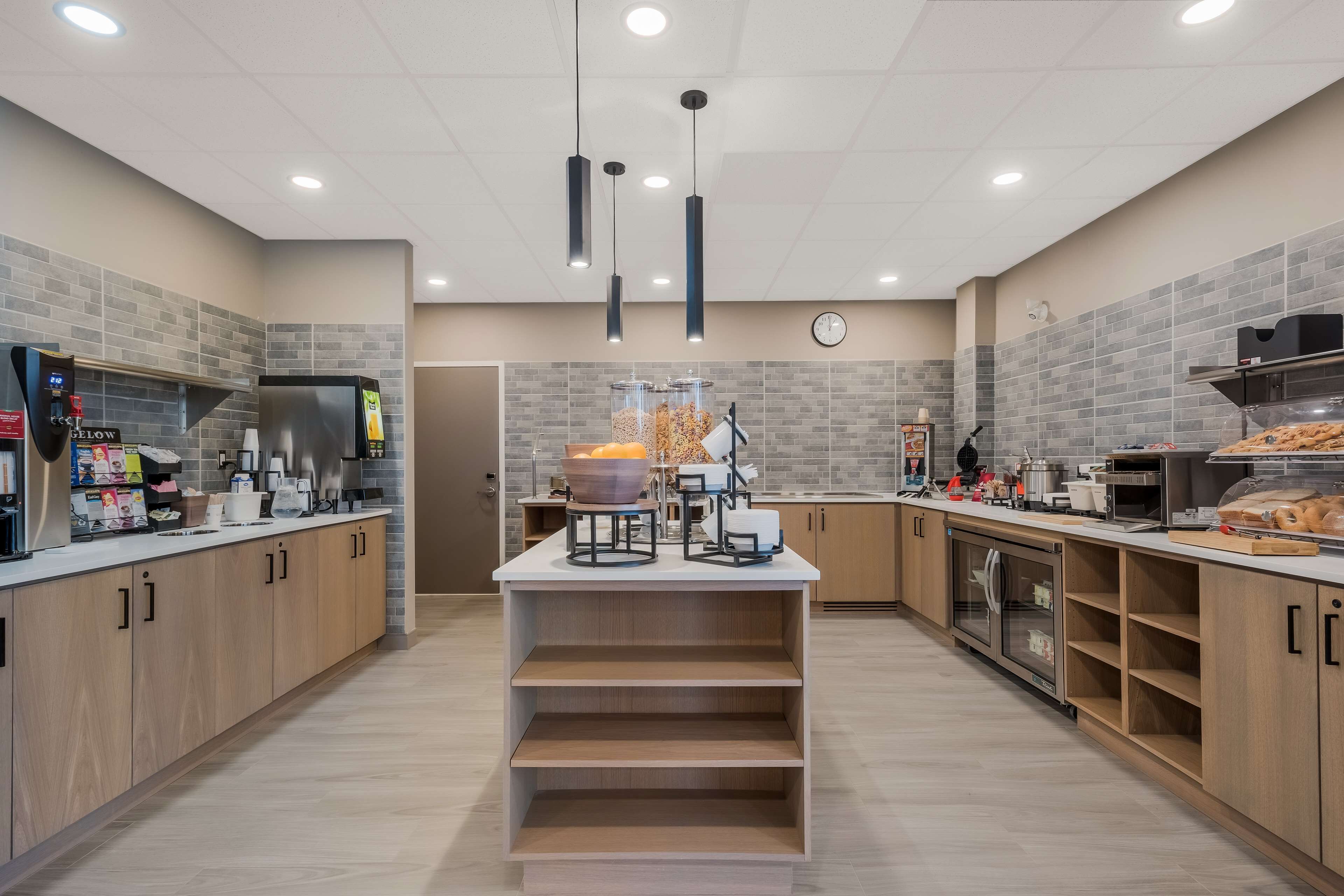 A modern kitchen with a central island, built-in appliances, and a clock on the wall.