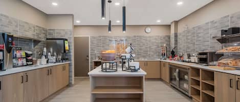 A modern kitchen with a central island, built-in appliances, and a clock on the wall.
