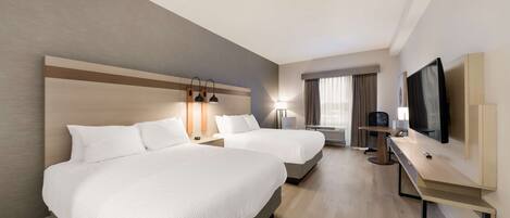 A hotel room with two beds, a desk, a TV, and a window with curtains.