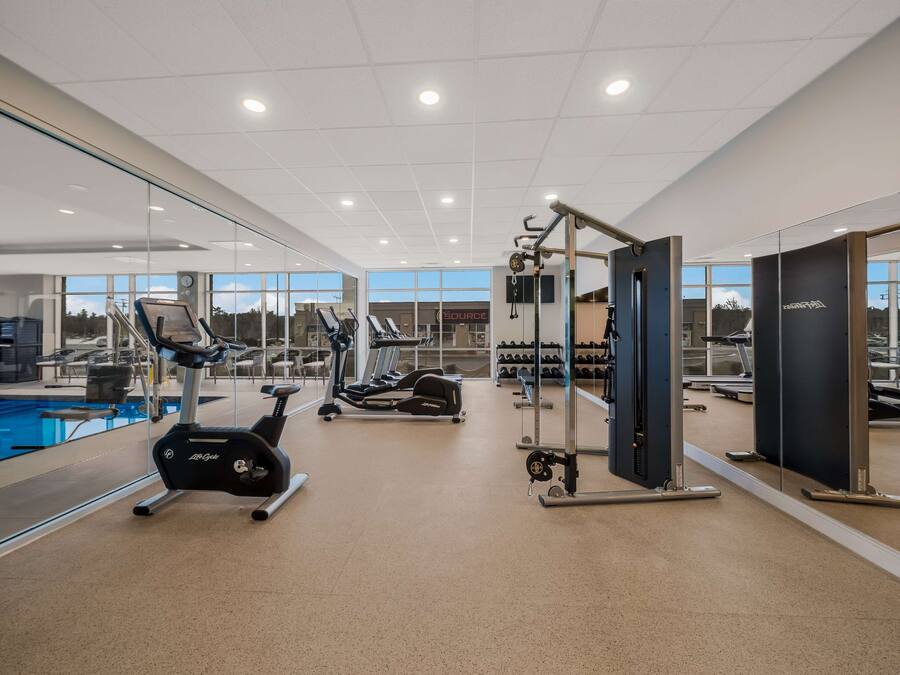 A modern gym with cardio machines, weightlifting equipment, and a pool.
