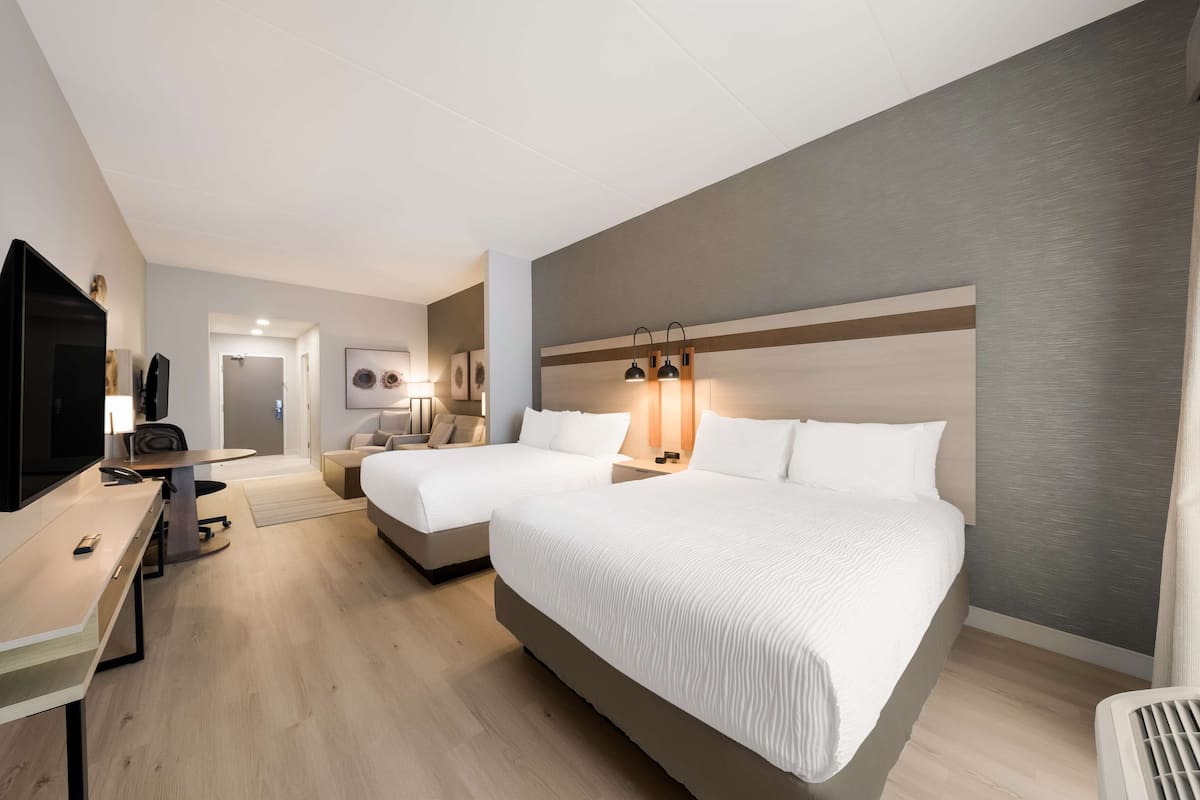 Ett hotellrum med två sängar, ett skrivbord med en tv och ett litet bord.
