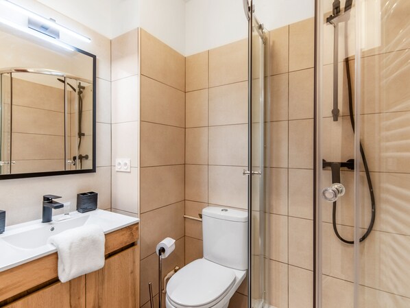 A modern bathroom with a glass-enclosed shower, a white toilet, and a sink with a towel.