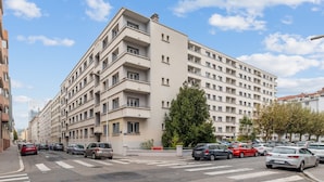 A multi-story residential building with a uniform facade, balconies, and a crosswalk in front. - Appartement de la Bannière - Welkeys (Lyon)