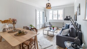 A modern living room with a dining area, a sofa, a coffee table, and a hanging light fixture. - Appartement de la Bannière - Welkeys (Lyon)