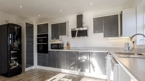 A modern kitchen with stainless steel appliances, a built-in oven, microwave, and a range hood. - Lie back and count the stars whilst lazing in the hot tub. (Gissing, near Diss)