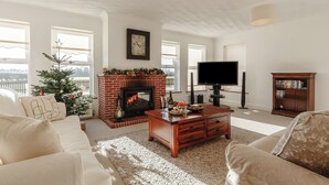 A living room with a fireplace, a television, and a bookshelf. - Lie back and count the stars whilst lazing in the hot tub. (Gissing, near Diss)