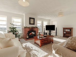Una sala de estar con chimenea, televisión y estantería.