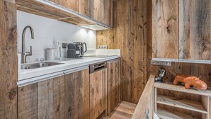 A modern kitchen with wooden cabinetry, a stainless steel sink, and a coffee maker.