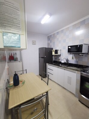 A compact kitchen with a refrigerator, microwave, stove, and a sink.