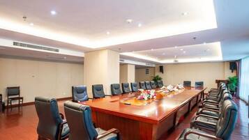 A conference room with a long table, multiple chairs, and a ceiling with recessed lighting.
