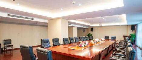 Un salón de conferencias con una mesa larga, varias sillas e iluminación empotrada en el techo.