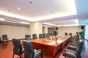 Un salón de conferencias con una mesa larga, varias sillas e iluminación empotrada en el techo.
