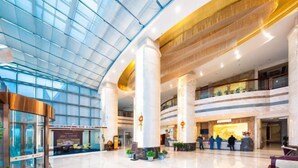 A spacious lobby with a high ceiling, large glass windows, and a reception area with a counter. - Jinhao International Hotel (Huaining)