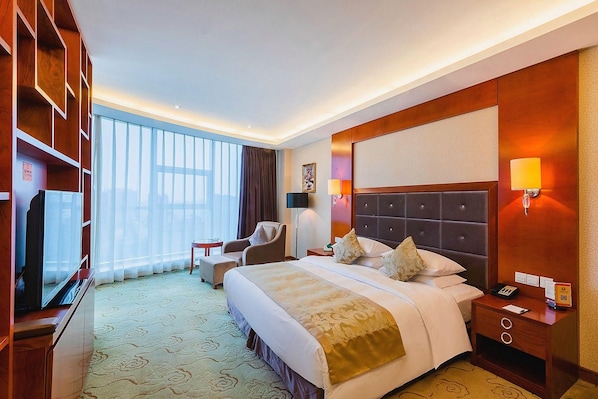 A hotel room with a large bed, bedside tables, a desk, and a chair. - Jinhao International Hotel (Huaining)
