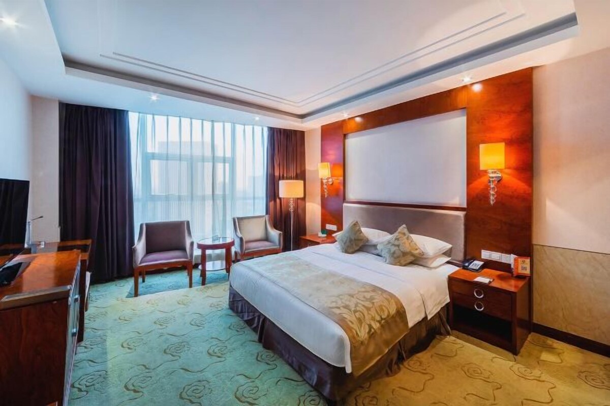 A hotel room with a large bed, two bedside tables, a desk, and a chair.