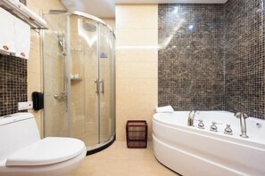A bathroom with a glass shower enclosure, a white toilet, and a large bathtub.