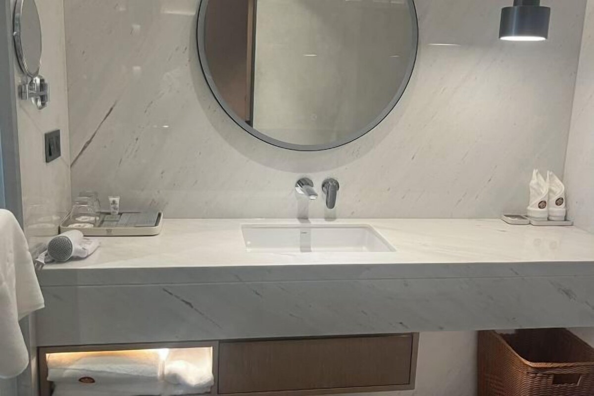 Een moderne badkamer met een ronde spiegel, een wastafel en een handdoekhouder.