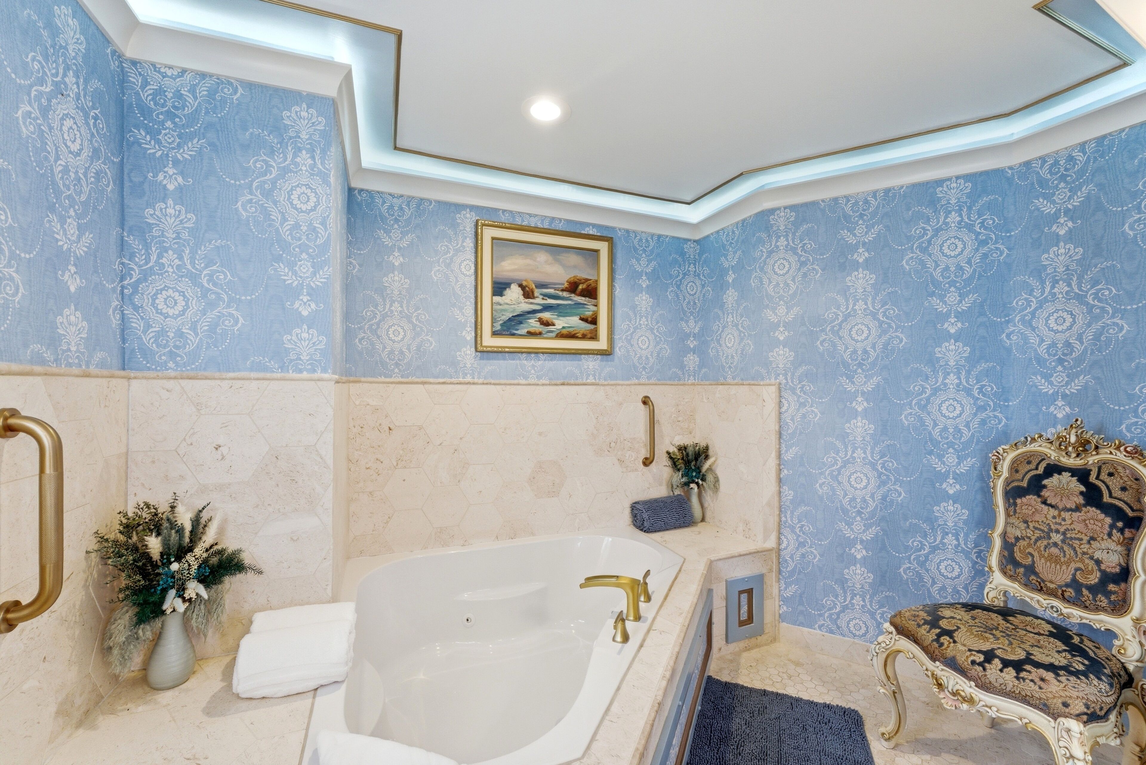 Ein Badezimmer mit einer Badewanne, einem Waschtisch mit Spiegel, einer Dekorationsvase und einem Stuhl.