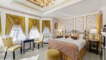 A luxurious bedroom with a large bed, ornate curtains, a chandelier, and a classic design.