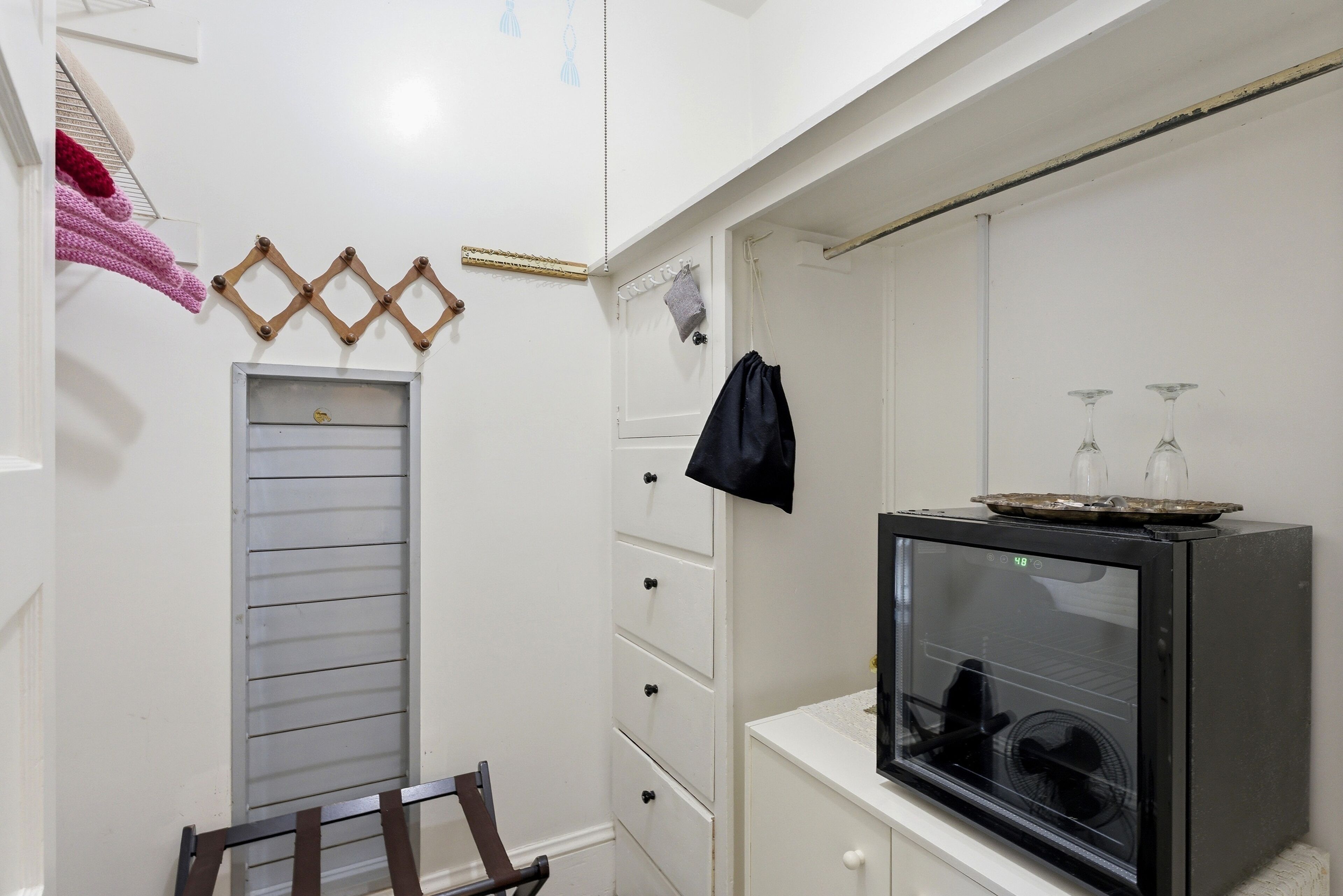 Una habitación pequeña con kitchenette, un televisor pequeño y una ventana con persianas.