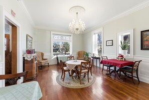 A dining room with a chandelier, wooden chairs, a round table, and a red tablecloth. - Heber Senator Bed and Breakfast (Heber City)
