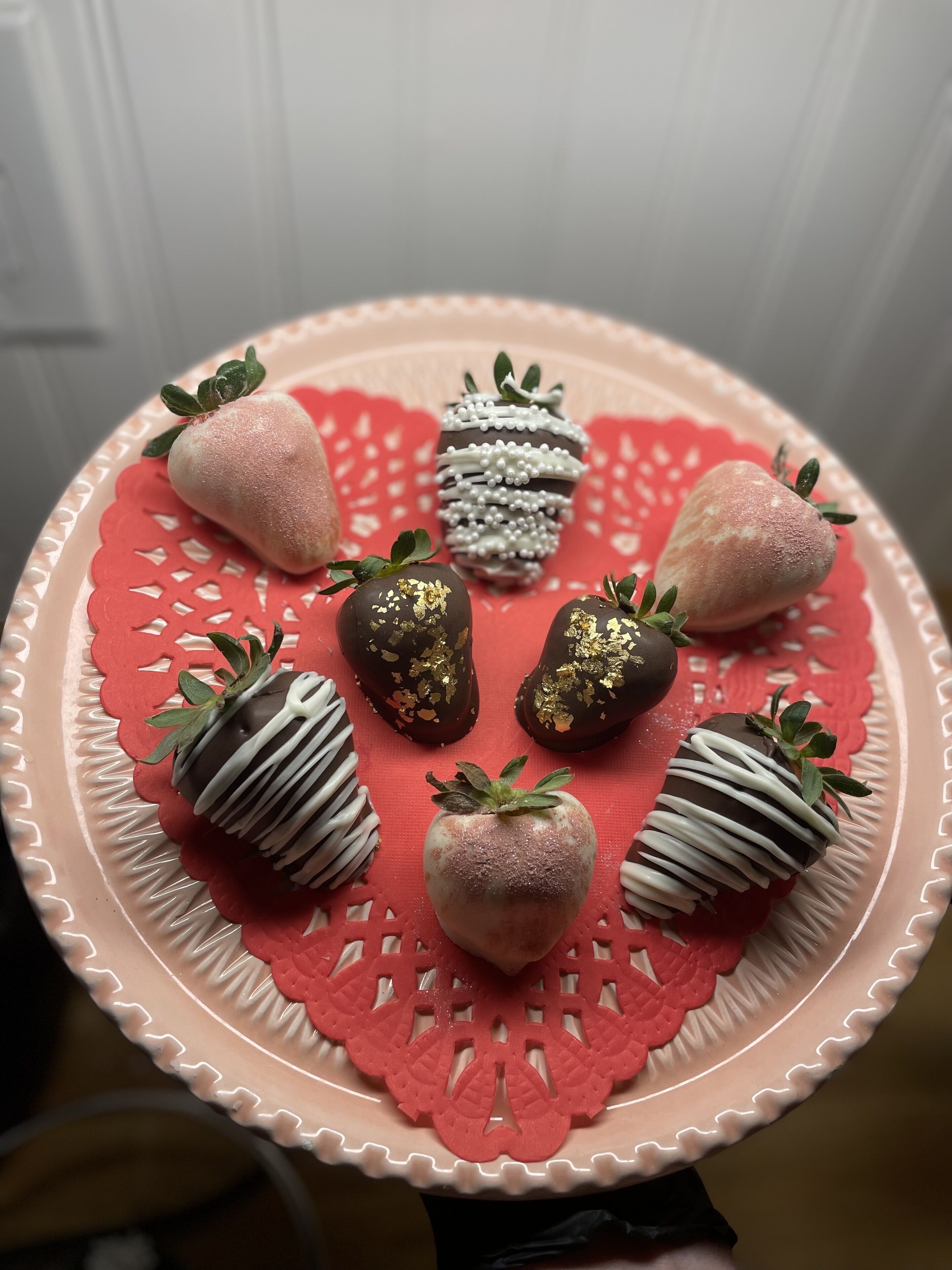 Un piatto di fragole con cioccolato e glassa bianca, disposto su un piatto decorativo.