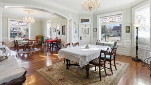 A spacious dining area with a chandelier, wooden chairs, and a table set for a meal. - Heber Senator Bed and Breakfast (Heber City)