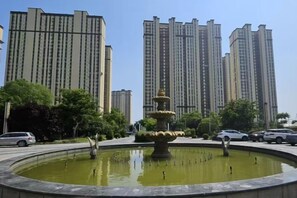A circular fountain with tiered water features surrounded by a paved area, with tall residential buildings in the background. - Dongming International Hotel (Dongming County)