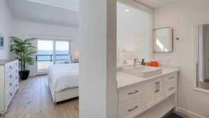 A bedroom with a bed, a dresser, a potted plant, and a view of the sea. - Beachfront Hideaway in Santa Barbara - 2 bedrooms, pool, spa, across from beach, gorgeous! (Santa Barbara)