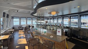 A modern restaurant with a bar area, large windows with a view of the water, and a high ceiling with exposed beams. - Beachfront Hideaway in Santa Barbara - 2 bedrooms, pool, spa, across from beach, gorgeous! (Santa Barbara)