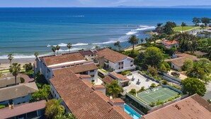 A coastal residential area with houses, a tennis court, and a view of the ocean. - Beachfront Hideaway in Santa Barbara - 2 bedrooms, pool, spa, across from beach, gorgeous! (Santa Barbara)