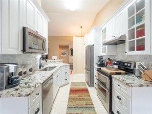 A modern kitchen with white cabinets, stainless steel appliances, and a granite countertop.