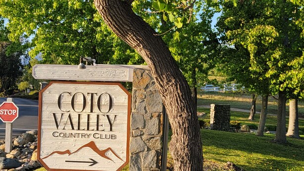 Ein Schild für den Coto Valley Country Club, in der Nähe ein Stoppschild.
