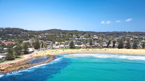 A coastal town with a beach, houses, and a rocky shoreline.