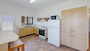 A compact kitchen with a stove, oven, microwave, and wooden cabinets.