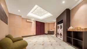 Quarto de hotel com um grande claraboia, área de estar com sofá, máquina de lavar e espaço para lavanderia.