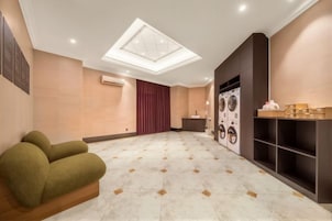 A hotel room with a large skylight, a seating area with a sofa, a washing machine, and a laundry station.