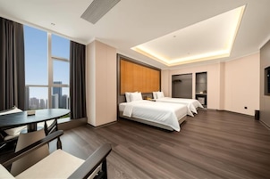 A hotel room with a bed, a desk, a chair, a window with a city view, and a modern ceiling design.