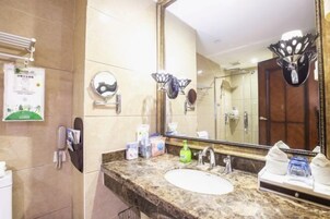 Un baño de hotel con un lavamanos de mármol, un espejo grande y un perchero para toallas.
