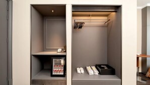 Um closet espaçoso com um sapateiro, uma prateleira pequena com uma garrafa e uma caixa.