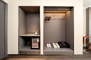 A walk-in closet with a shoe rack, a small shelf with a bottle, and a box.