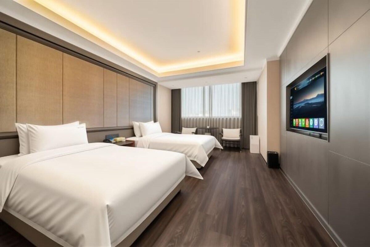 A hotel room with two beds, a flat-screen TV, a desk, and a chair.