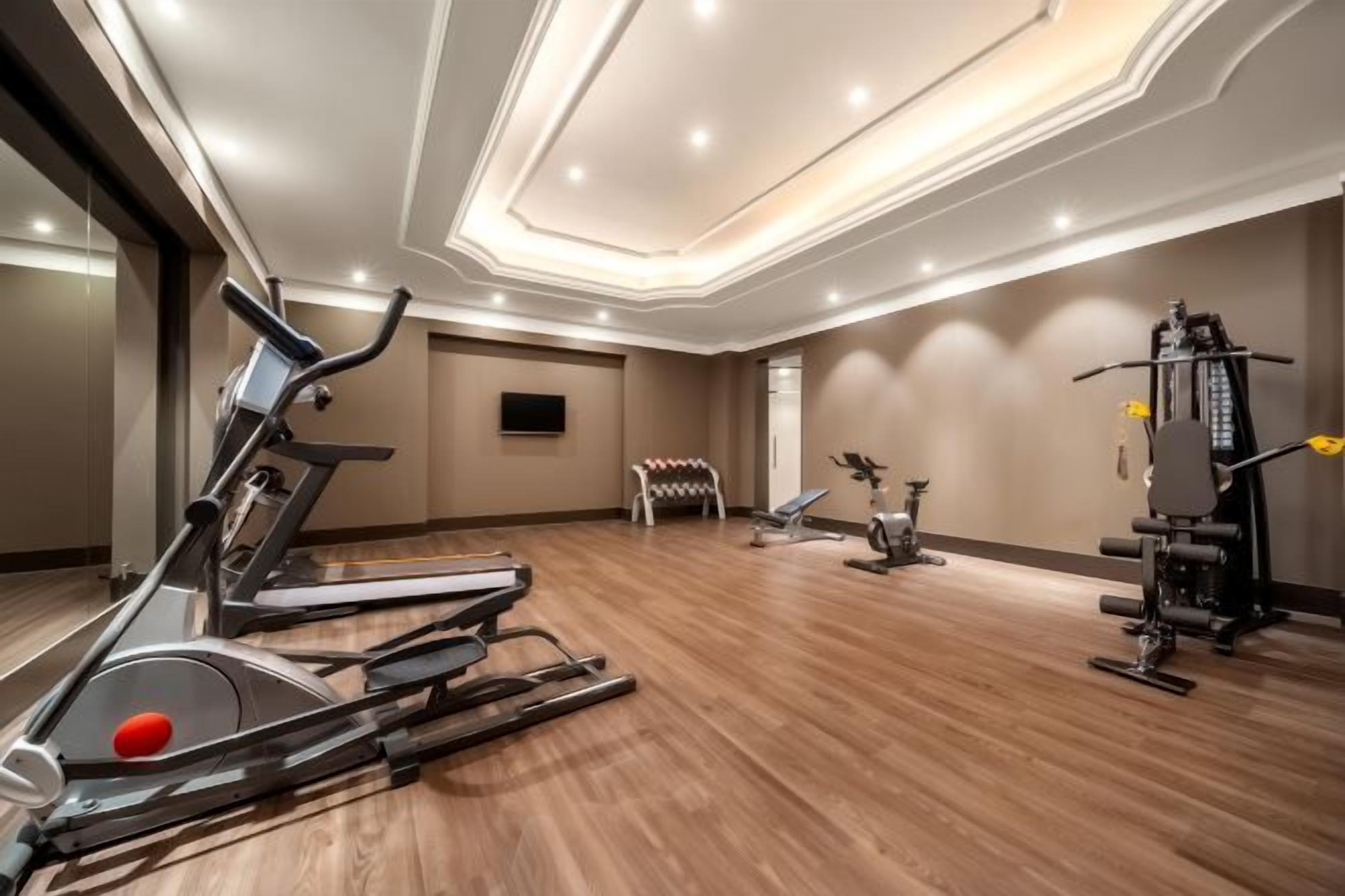 Un gimnasio con cintas de correr, bicicletas estáticas y máquinas de pesas.