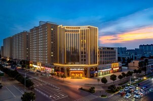 A multi-story hotel with a prominent entrance and a parking lot.
