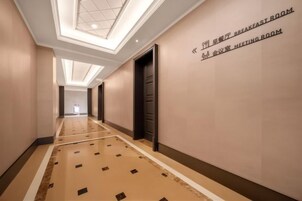 A hotel corridor with a ceiling light fixture, a sign indicating a breakfast room, and a meeting room.