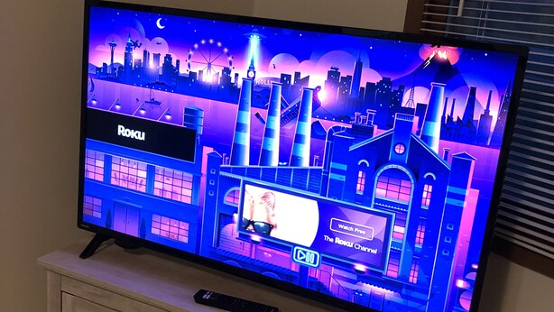 Un televisor sobre un mueble de madera con un control remoto.