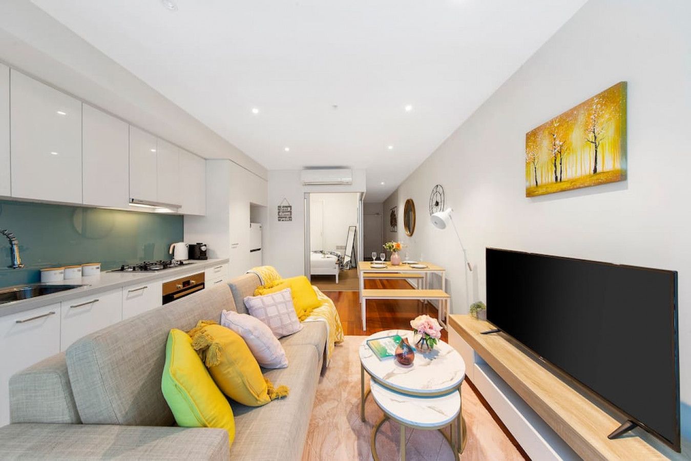 A modern apartment with a living room, kitchen, dining area, and a TV.