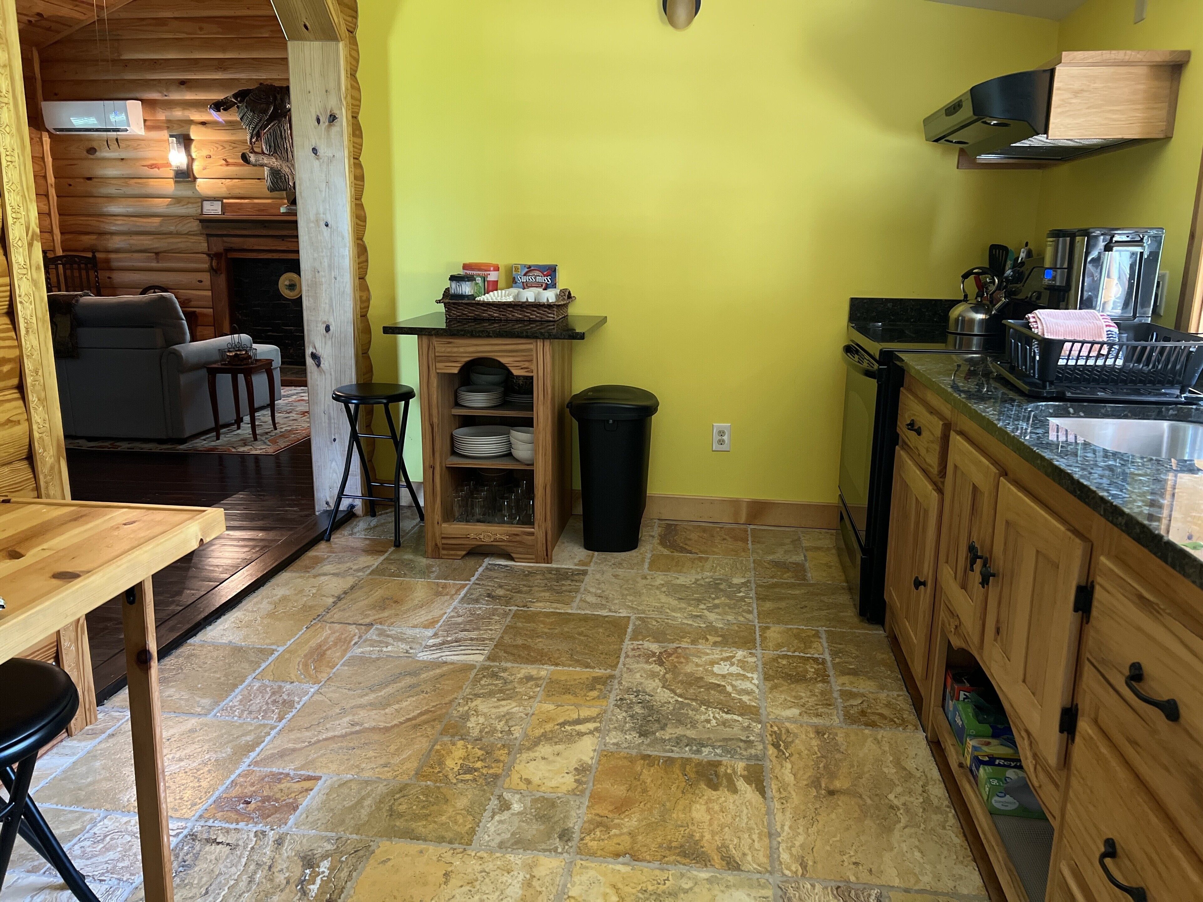 Una cocina compacta con suelo de baldosas de piedra, armarios de madera y estufa empotrada.